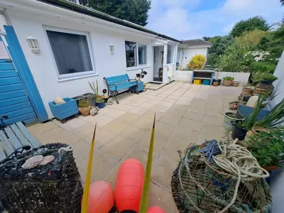 a patio with a blue bench and some plants at Willow Bungalow Quiet and secluded in Carbis Bay