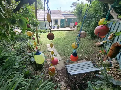 a garden with a swing and a bench and fruits at Willow Bungalow Quiet and secluded in Carbis Bay