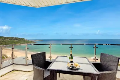 a table on a balcony with a view of the beach at Blue Vista in Carbis Bay