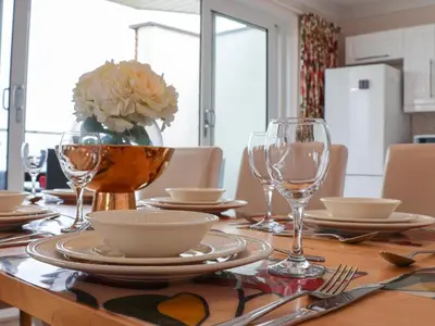 a table with glasses and plates and a vase with flowers at Blue Vista in Carbis Bay