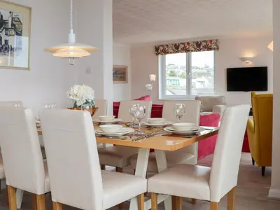 a dining room with a wooden table and white chairs at Blue Vista in Carbis Bay