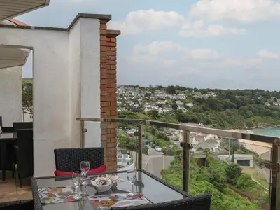 a table with wine glasses on a balcony with a view at Blue Vista in Carbis Bay