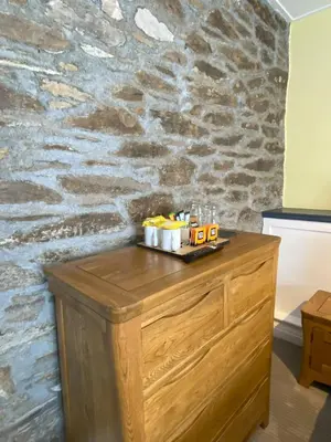 a wooden dresser in a room with a stone wall at Jubilee Inn in Looe