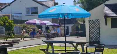 a picnic table with a blue umbrella in a yard at Jubilee Inn in Looe