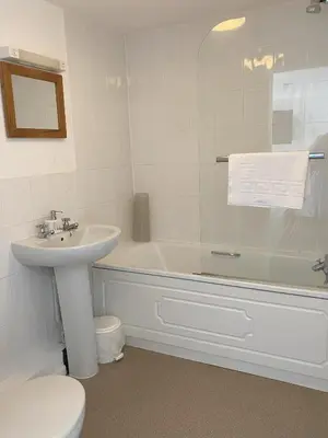 a bathroom with a sink and a tub and a toilet at Jubilee Inn in Looe