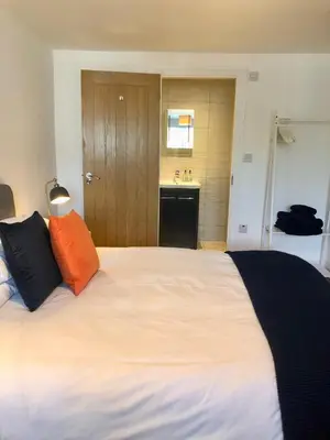 a bedroom with a large white bed with an orange pillow at Guest Room with Parking Near St Ives & Penzance in Penzance
