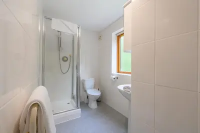 a white bathroom with a shower and a toilet at Golf View 80 in Camborne