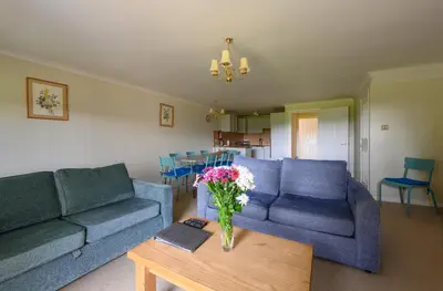 a living room with blue couches and a vase of flowers on a table at Golf View 80 in Camborne