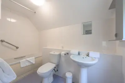 a white bathroom with a toilet and a sink at Golf View 80 in Camborne