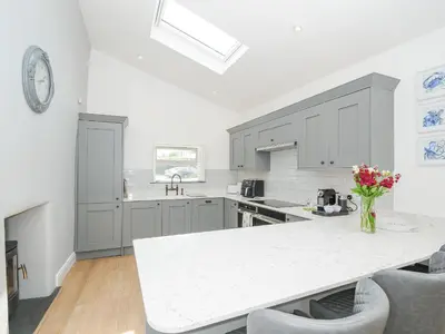 a kitchen with gray cabinets and a white counter top at Cob Cottage in Wadebridge