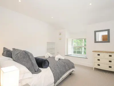 a white bedroom with a bed and a window at Cob Cottage in Wadebridge