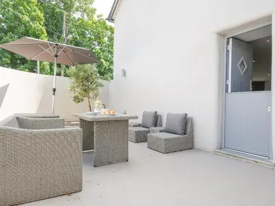 a patio with a table and chairs and an umbrella at Cob Cottage in Wadebridge