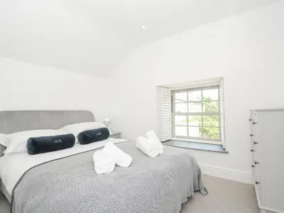 a white bedroom with a bed with towels on it at Cob Cottage in Wadebridge