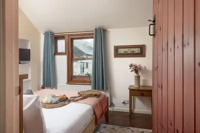 a bedroom with a bed with a window and a table at Cosy Cottage in St Ives, Wi-Fi, Pets Accepted in St Ives