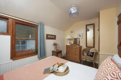a bedroom with a bed with a table and a window at Cosy Cottage in St Ives, Wi-Fi, Pets Accepted in St Ives