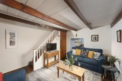 a living room with a blue couch and a table at Cosy Cottage in St Ives, Wi-Fi, Pets Accepted in St Ives