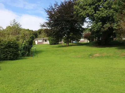 a yard with a swing set in the grass at Villa 18 Lanteglos Holiday Park in Camelford