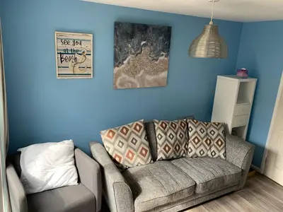 a living room with a couch and a blue wall at Tolroy Manor - 84 Strawberry Hill in Hayle