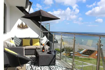 a balcony with a couch and an umbrella at Apartment 19 in Downderry