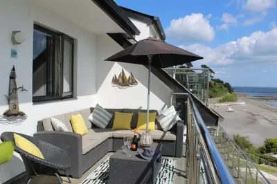 a balcony with a couch and an umbrella at Apartment 19 in Downderry