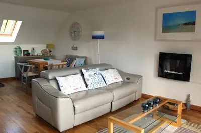 a living room with a couch and a table at Apartment 19 in Downderry