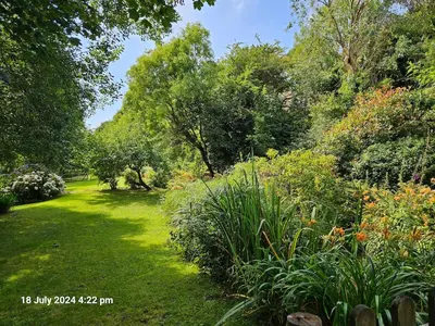 a garden with lush green grass and trees at Spacious Farmhouse between St Agnes & Porthowan in Truro