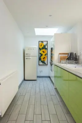 a kitchen with green cabinets and a refrigerator at Spacious Farmhouse between St Agnes & Porthowan in Truro