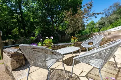 three chairs and a table in a garden at Spacious Farmhouse between St Agnes & Porthowan in Truro