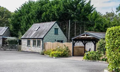 a green house with a fence and a wooden gate at Little Willow in Saint Columb Major