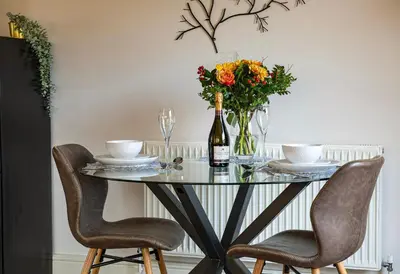 a dining room table with a bottle of wine and flowers at Little Willow in Saint Columb Major