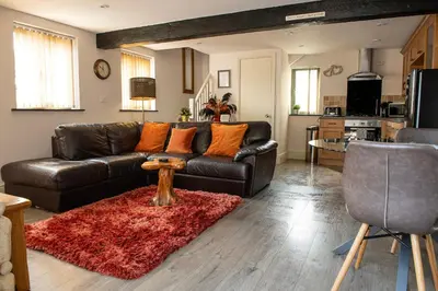a living room with a leather couch and a table at Little Willow in Saint Columb Major