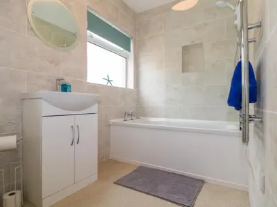 a bathroom with a tub and a sink and a mirror at Small Hillman in Perranporth