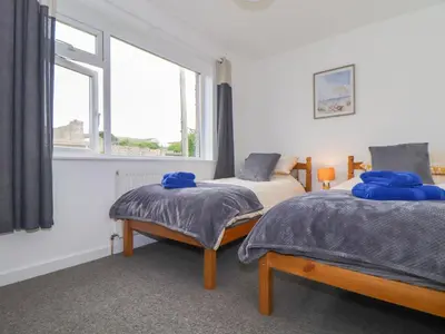 a bedroom with two beds and a window at Small Hillman in Perranporth