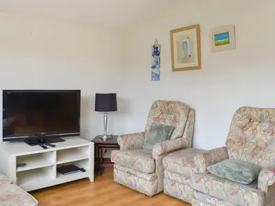 a living room with two chairs and a flat screen tv at Mother Ivy's Bay - Uk47553 in St Merryn