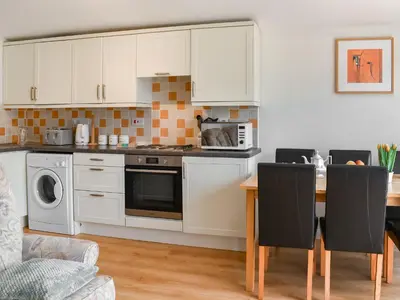 a kitchen with white cabinets and a table with chairs at Mother Ivy's Bay - Uk47553 in St Merryn