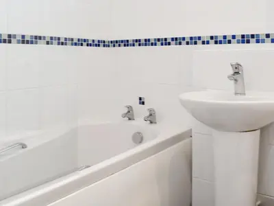 a white bathroom with a sink and a bath tub at Mother Ivy's Bay - Uk47553 in St Merryn