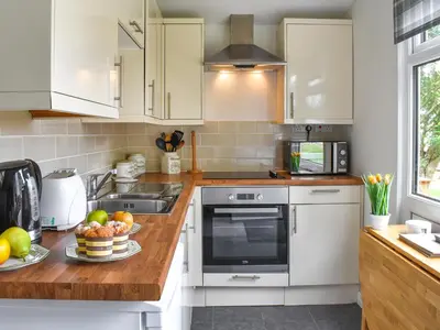 a kitchen with white cabinets and a bowl of fruit at Trevose Head - Uk47556 in St Merryn