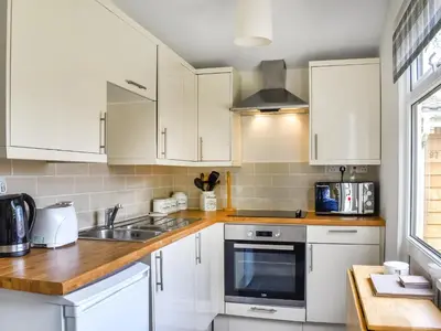 a kitchen with white cabinets and a sink at Trevose Head - Uk47556 in St Merryn