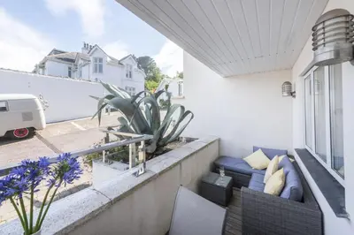 a balcony with a blue couch and a plant at Apartment By The Sea, Wi-Fi, Pets Accepted in St Ives