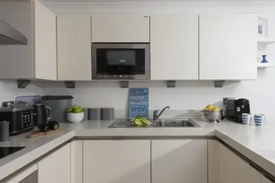 a white kitchen with a sink and a microwave at Apartment By The Sea, Wi-Fi, Pets Accepted in St Ives
