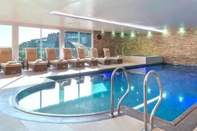 a large swimming pool in a building with chairs at Apartment By The Sea, Wi-Fi, Pets Accepted in St Ives