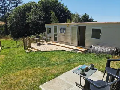 a backyard with a cabin with a deck and a table at Meadow Bluebird in Bodmin