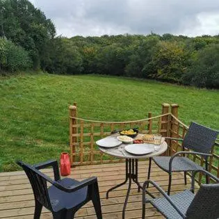 a table and chairs on a deck with a field at Meadow Bluebird in Bodmin