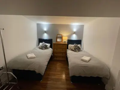 a bedroom with two beds and a dresser at No1 Apartment Mevagissey in Mevagissey
