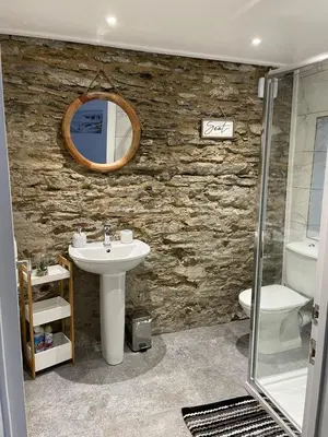 a stone bathroom with a sink and a mirror at No1 Apartment Mevagissey in Mevagissey