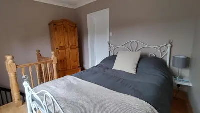 a bedroom with a bed and a wooden cabinet at Driftwood in Looe River view and parking in Looe