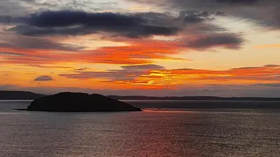 a sunset over a large body of water at Driftwood in Looe River view and parking in Looe