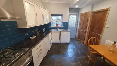 a kitchen with white cabinets and a blue tile floor at Driftwood in Looe River view and parking in Looe