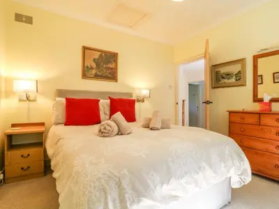 a bedroom with a large white bed with red pillows at Jordan Cottage in Fowey