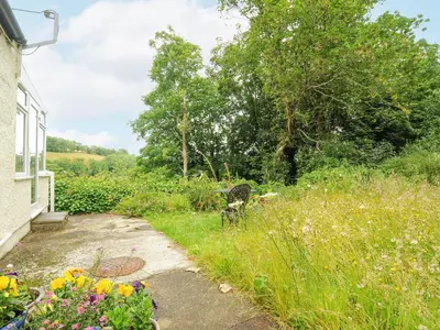 a path leading to a garden with flowers at Jordan Cottage in Fowey